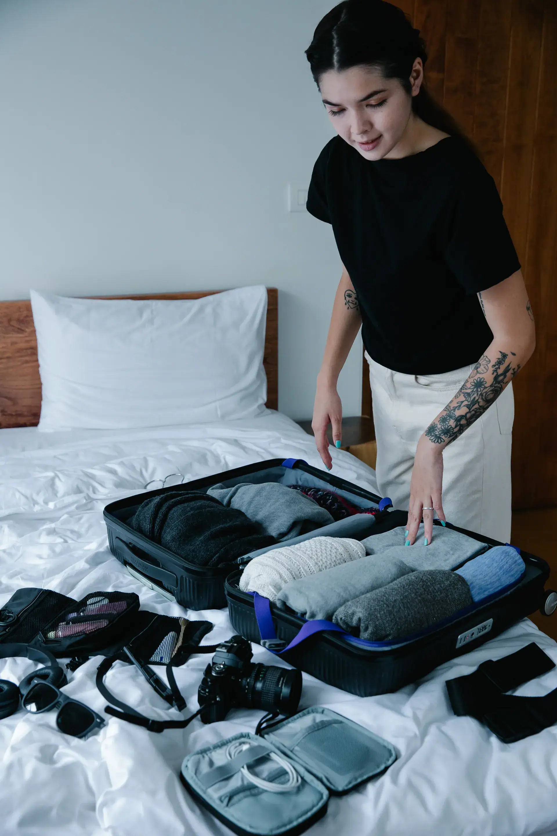 Estudiante haciendo la maleta sobre la cama con la ropa doblada